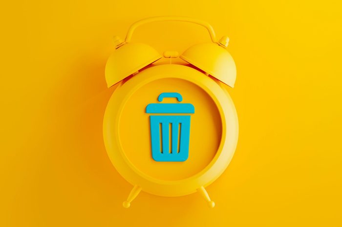 yellow alarm clock on yellow background with blue trash can symbol