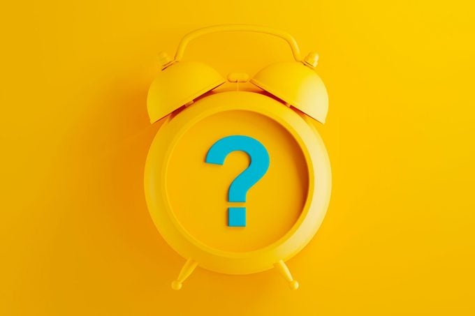 yellow alarm clock on yellow background with blue question mark symbol