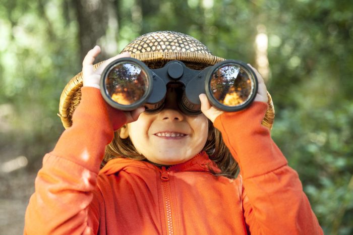 Six years old girl close up, looking through binoculars.