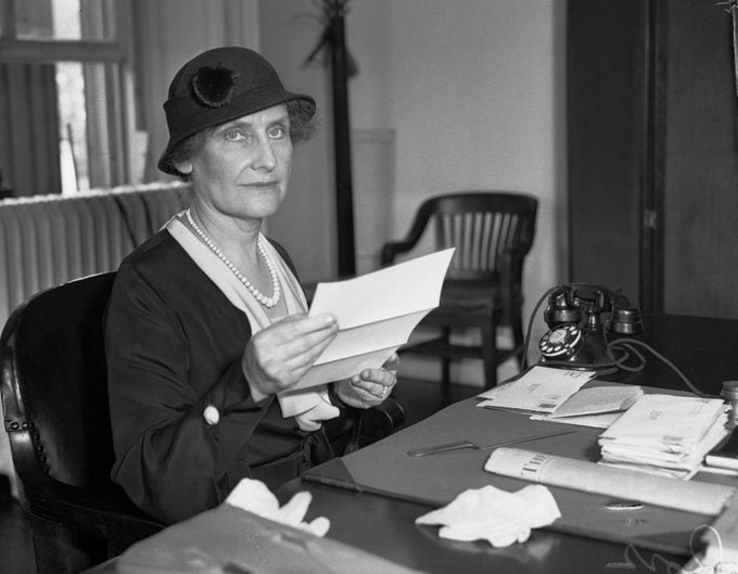 First Woman Director Of The U. S. Mint. Mrs. Nellie Tayloe Ross, former Governor of Wyoming, seated at her desk in the U. S. Treasury Building as she assumes her new duties as Director of the Mint.