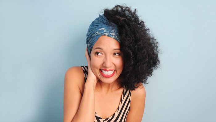young woman in a headscarf. shy and/or embarassed. on blue-gray background