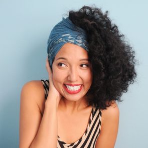 young woman in a headscarf. shy and/or embarassed. on blue-gray background