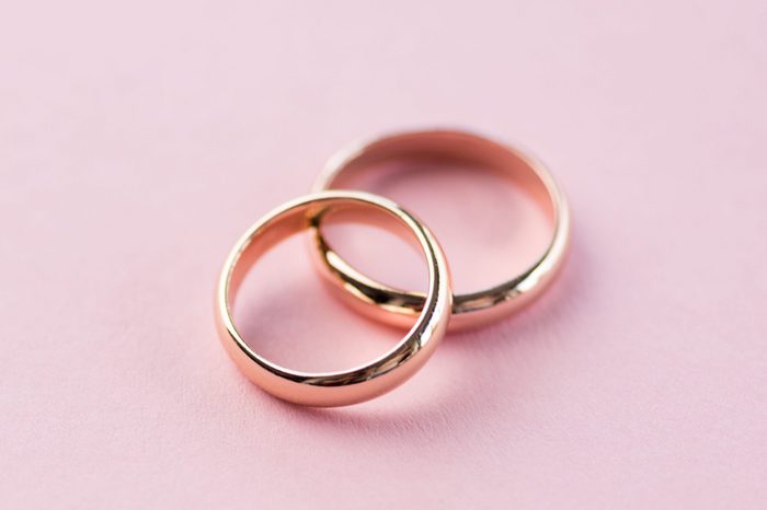 Close-up view of shiny golden wedding rings on pink background