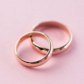 Close-up view of shiny golden wedding rings on pink background
