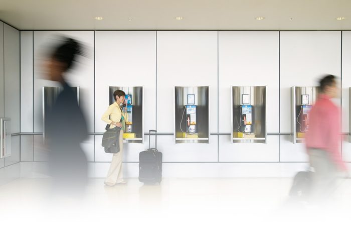 people walk past as a woman used a payphone at an airport