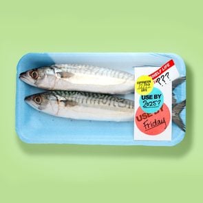 Packaged fish with expiration date stickers on a green background