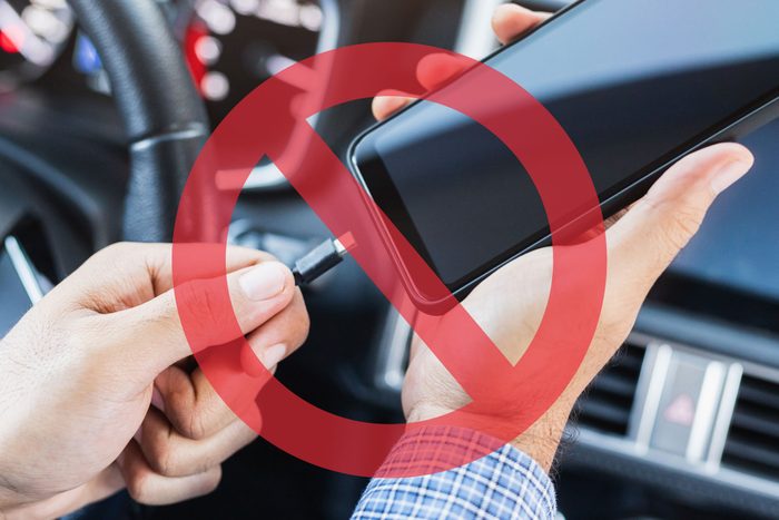 hands of a man plugging in a smartphone in a rental car; no sign overlay on top of the image