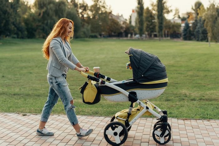 Mother enjoying walk carrying her little child in his baby trolley.
