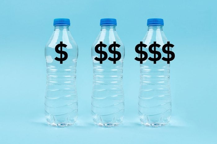 three plastic water bottles with "$" "$$" and "$$$" on blue background