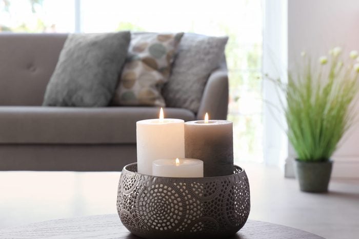 Vase with burning candles on table in living room