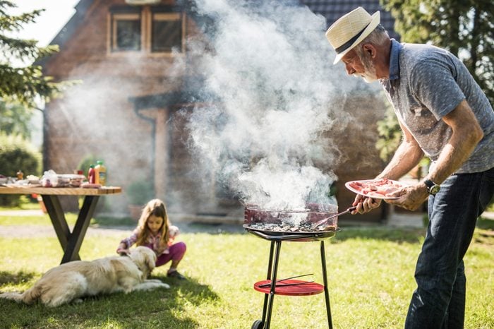 Mature man preparing barbecue for his grandkid in the backyard. Focus is on man.