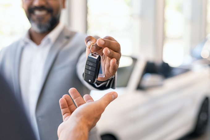 Salesman giving new car keys to customer