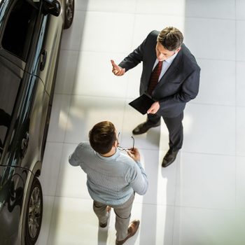 Above view of car salesperson talking to his customer in a showroom.