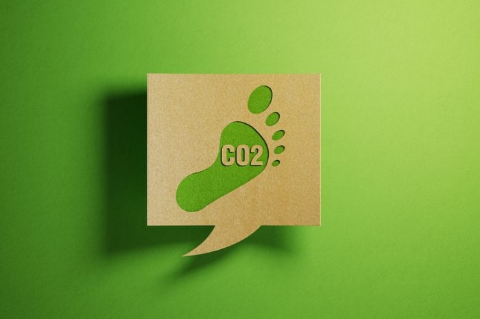 Carbon Footprint Icon on A Chat Bubble Which Is Made of Recycled Paper Over Green Background