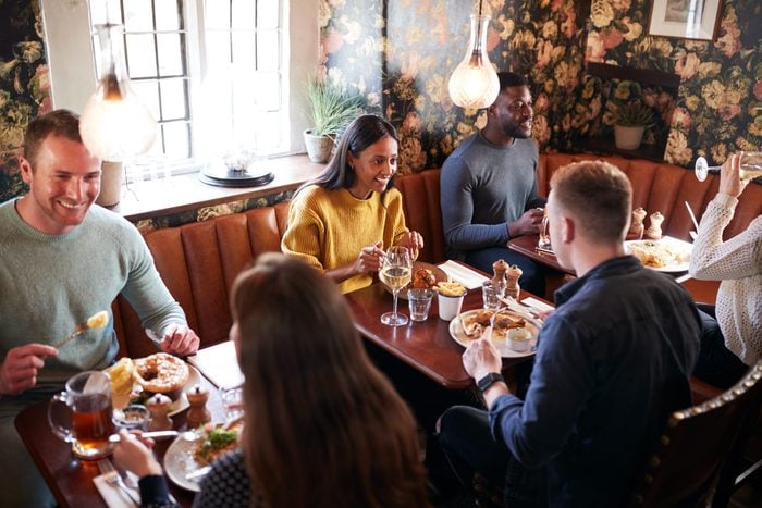 Group Of People Eating In Restaurant Of Busy Traditional English Pub