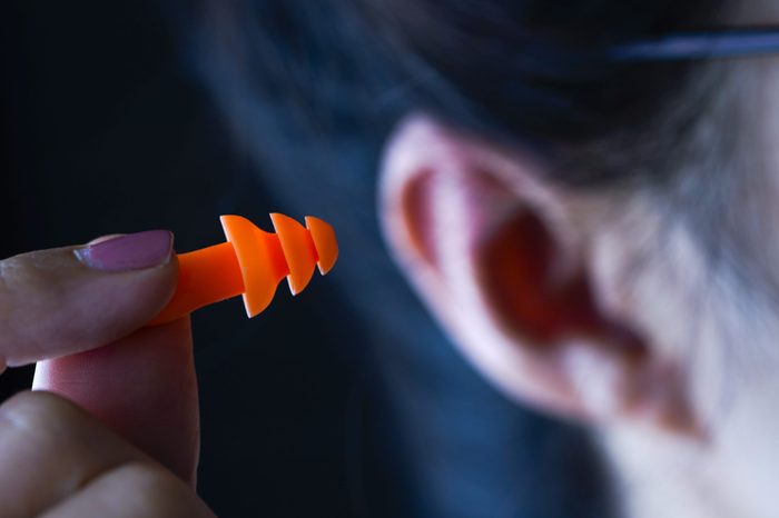 Female hand putting orange earplugs