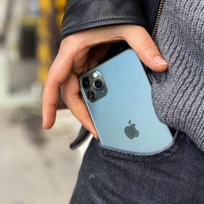 man's hands pulling iphone 11 out of pocket. close up.