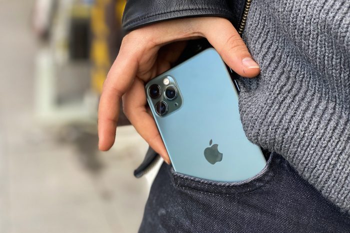 man's hands pulling iphone 11 out of pocket. close up.
