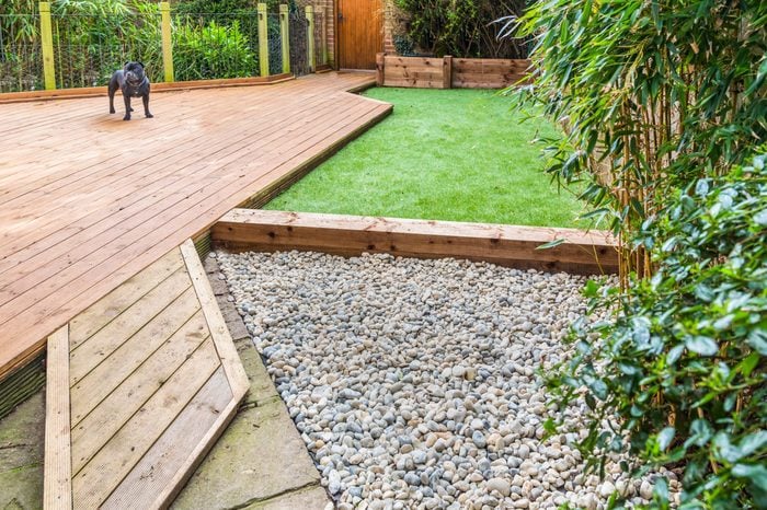 A section of a residntial garden, yard with wooden decking and artificial grass