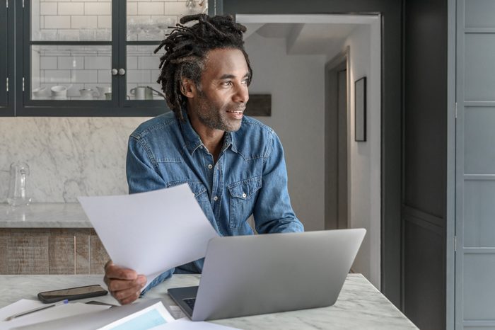 Confident businessman in his 50s working from home with laptop and paperwork