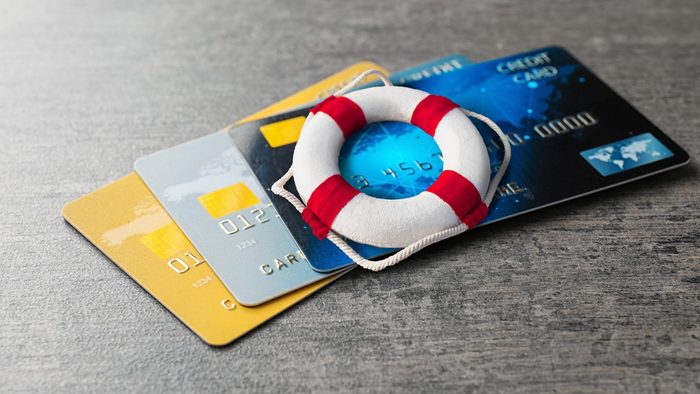 three credit cards on and a miniature life preserver on a wooden desk