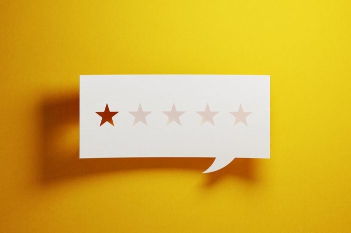 Feedback Concept - White Chat Bubble With Cut Out Star Shapes Over Yellow Background