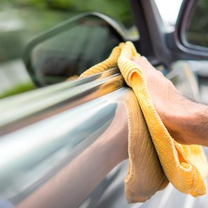 A man cleaning a car with yellow microfiber cloth - car detailing, vale and auto service concept