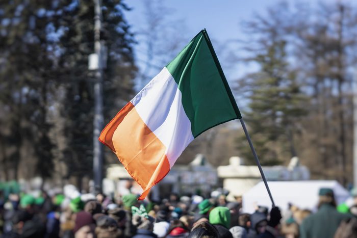 Flag of Ireland close-up in hands on background of blue sky during the celebration of St. Patrick's Day