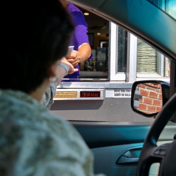 Fast food employee and customer hands in a transaction at the drive thru