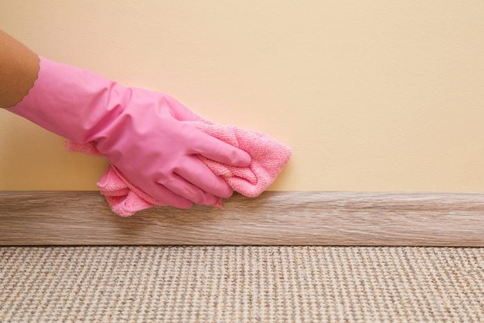 Pink glove with pink towel Cleaning Baseboard in a house
