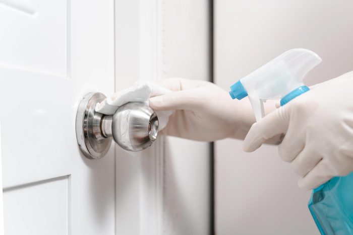 Hand with clear gloves disinfects door knob in a house during spring cleaning