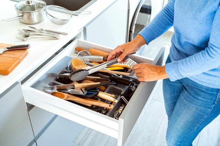 Woman in blue jeans Cleans Kitchen Drawers for spring cleaning