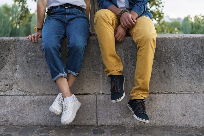 Legs of a couple sitting on a wall