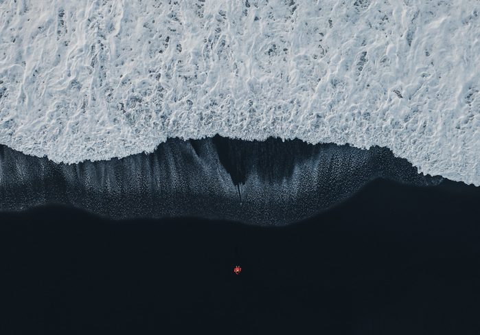 Aerial view of woman on black sand beach in Iceland