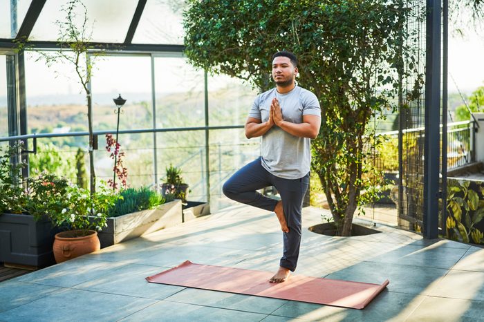 man practicing yoga outside at home