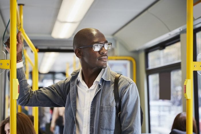 Confident male commuter looking away while standing in tram