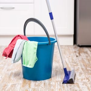 Plastic bucket with cleaning supplies in home
