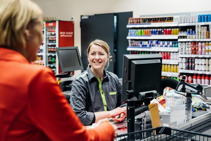 Cashier Smiling At Customer Buying Groceries