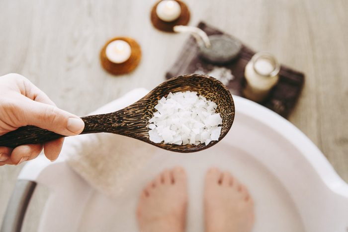Adding Magnesium Chloride vitamin salt in foot bath water, solution. Magnesium grains in foot bath water are ideal for replenishing the body with this essential mineral, promoting overall wellbeing.