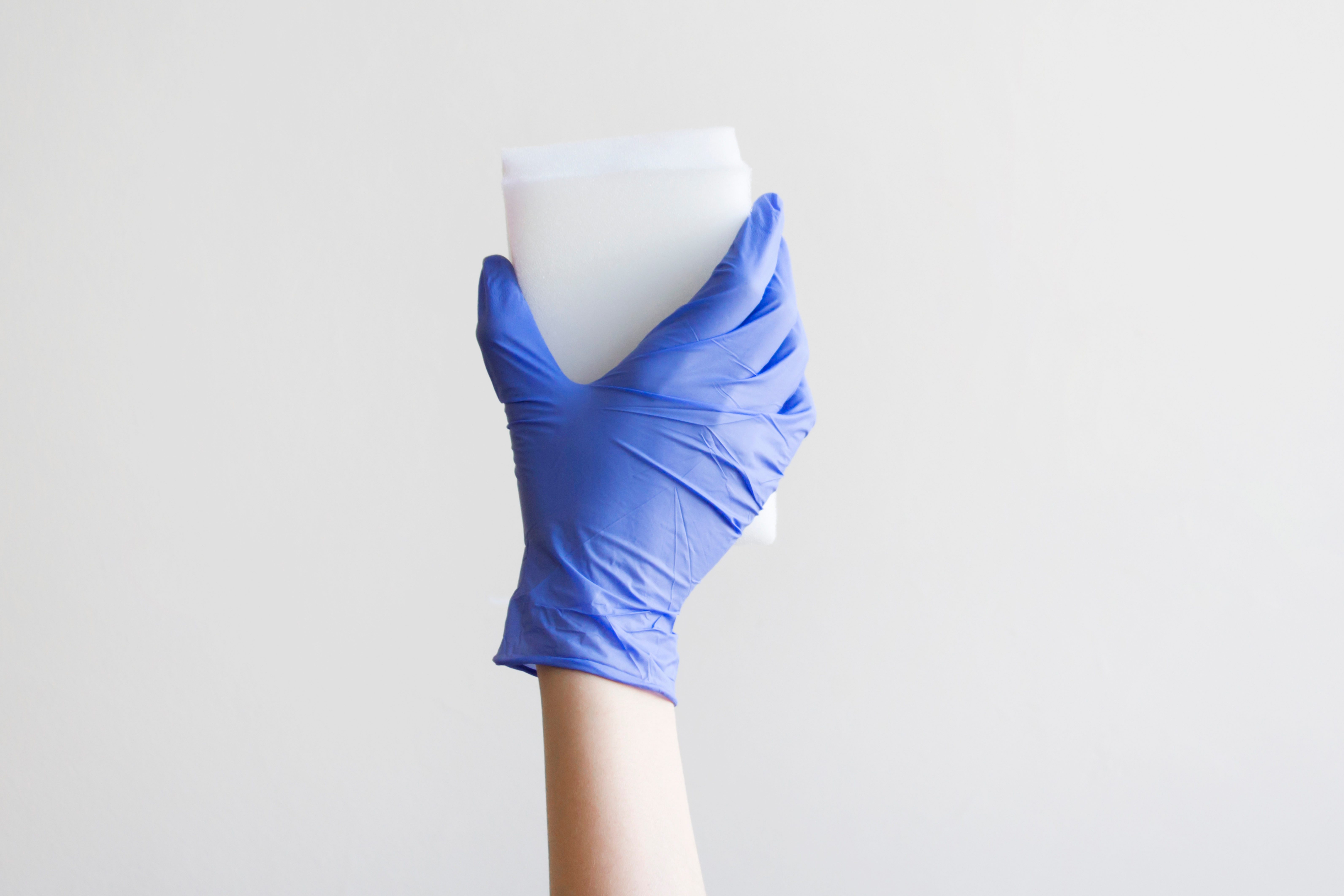 Woman hand holding a cleaning sponge isolated on a gray background