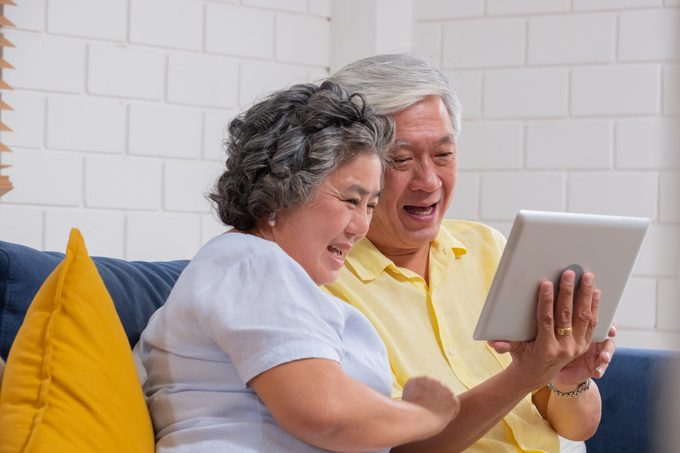 Asian senior couple use tablet video call and talk to grandchild