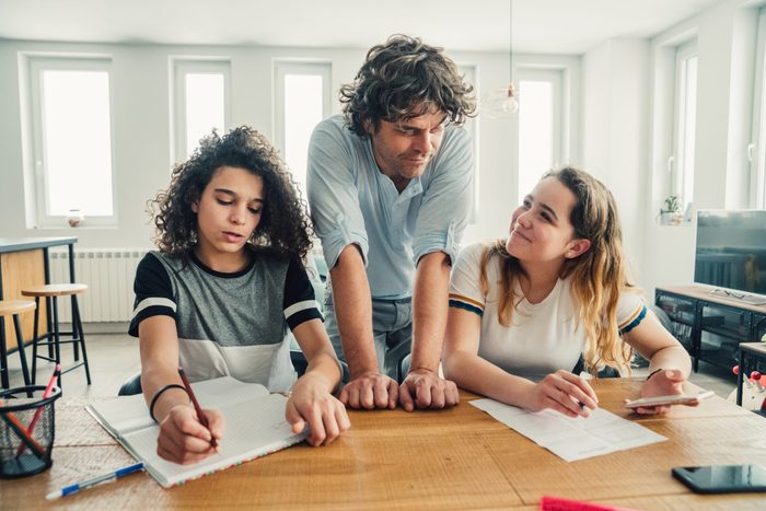 Father helping his daughter and son to finish homework