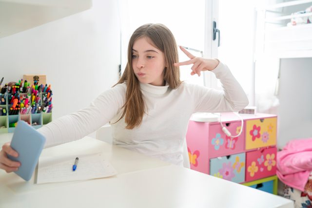 Teenager student girl selfie with smartphone at homework