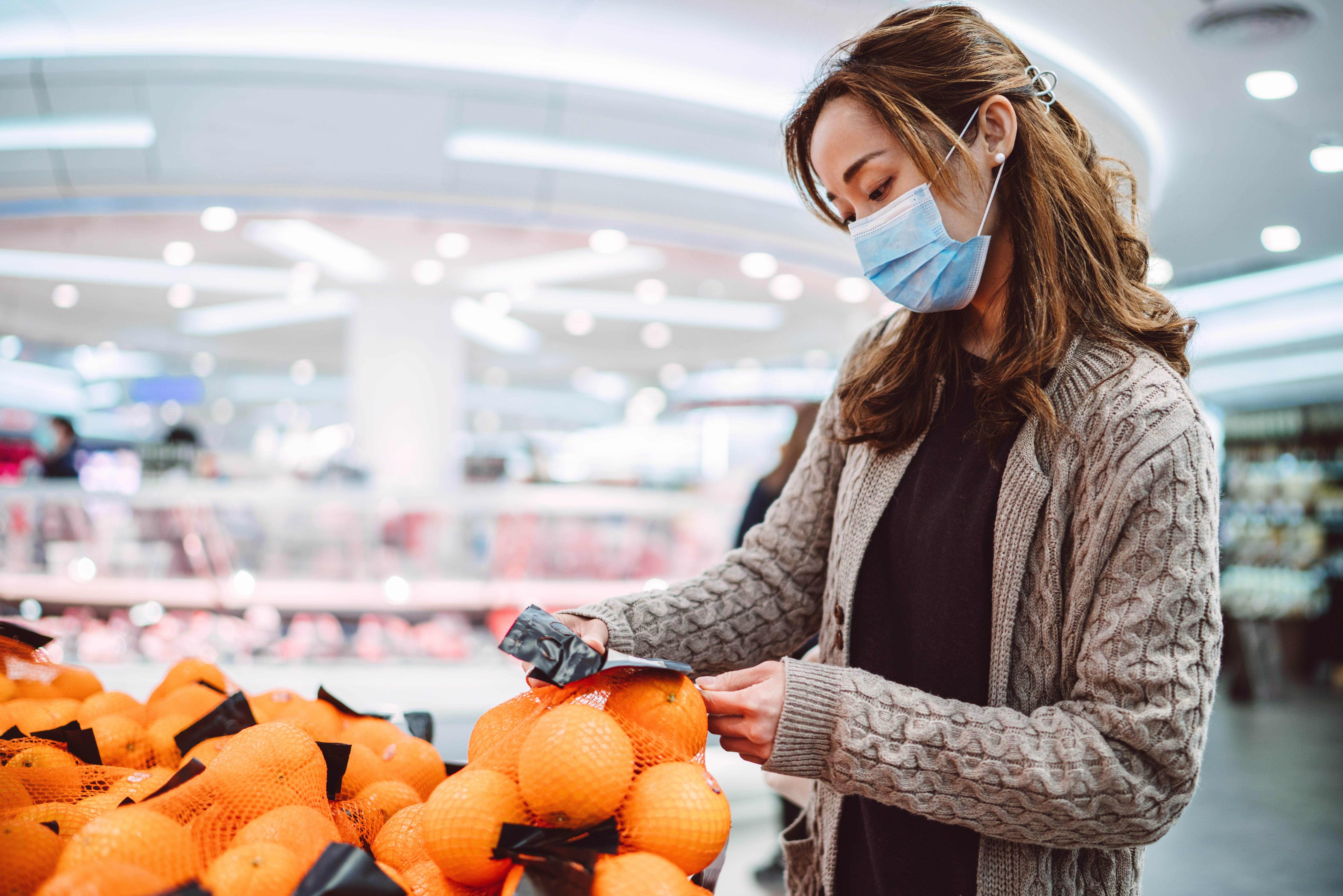 Young asian lady in medical face mask shopping in a supermarket