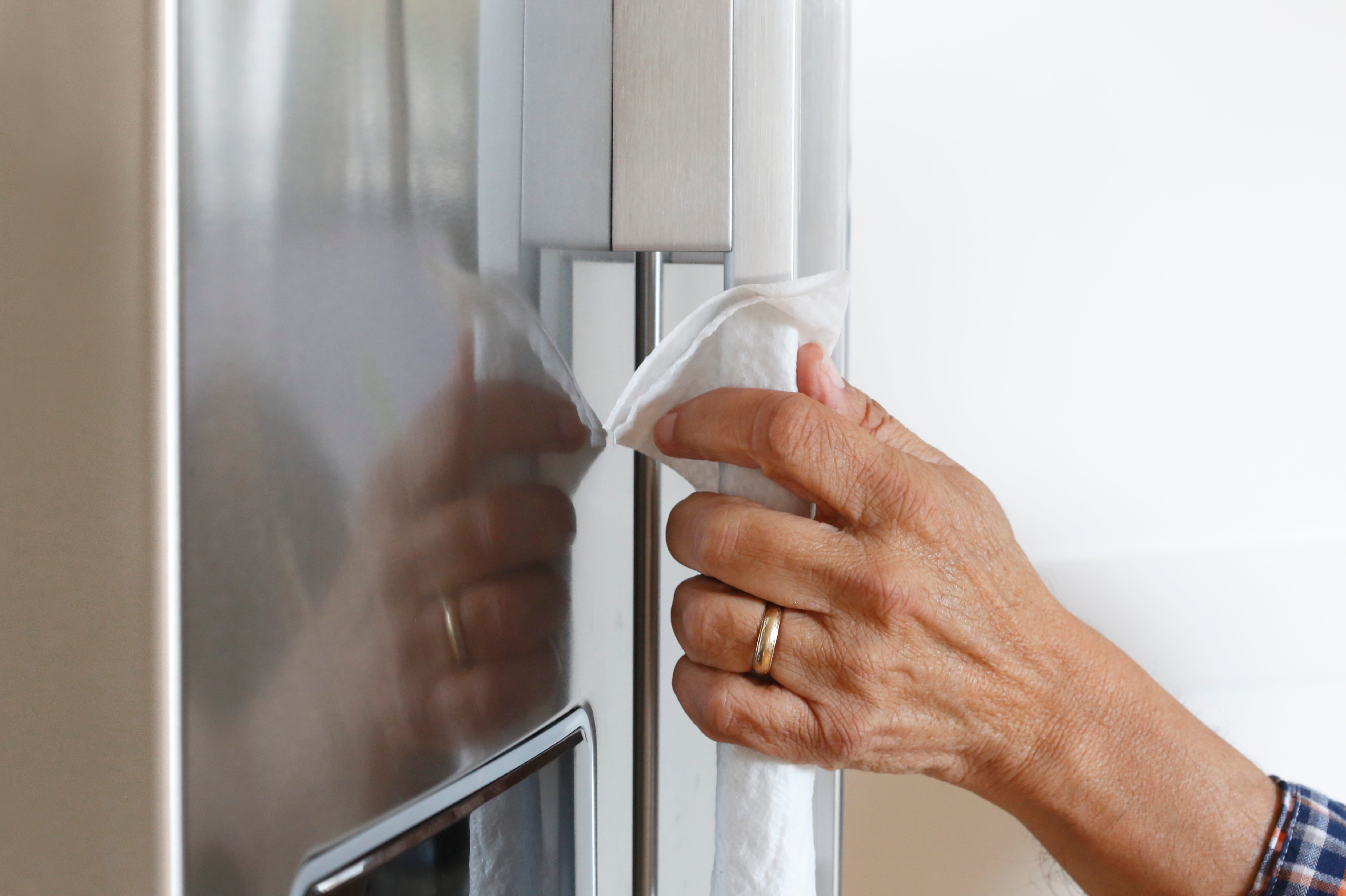 Close Up Of Man Cleaning Refrigerator With Disinfectant Wipe