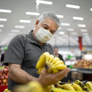 Senior man with disposable medical mask shopping in supermarket