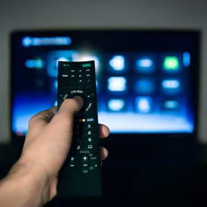 Male hand using Tv remote control