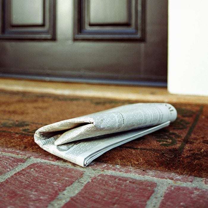 Newspaper on front step of house