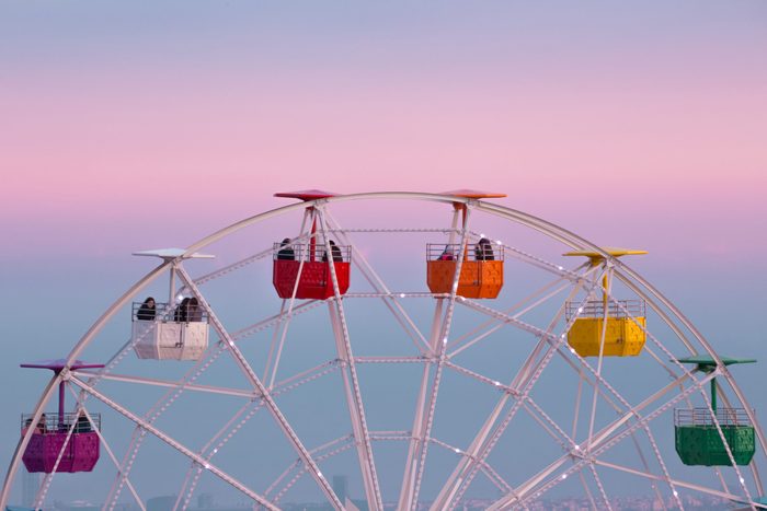 Colorful ferris wheel in the Tibidabo amusement park mountain with the Barcelona city view and the pink sunset sky.