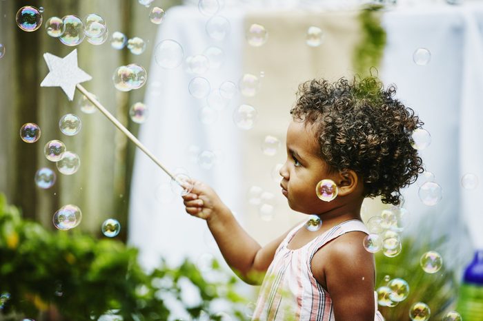 Toddler girl with star wand playing with bubbles
